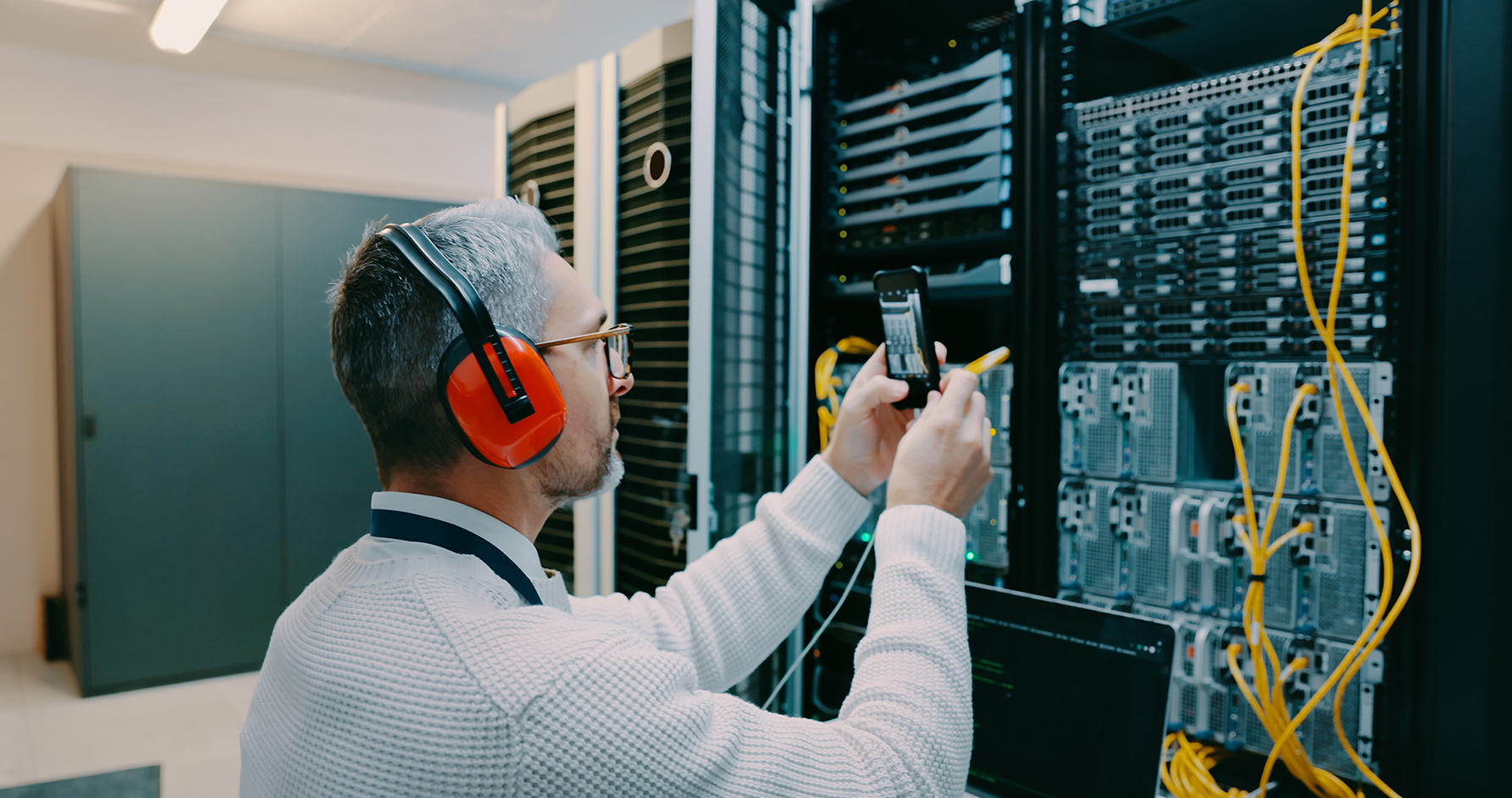 Shot of a male technician using his smartphone to take a photo in a server room.