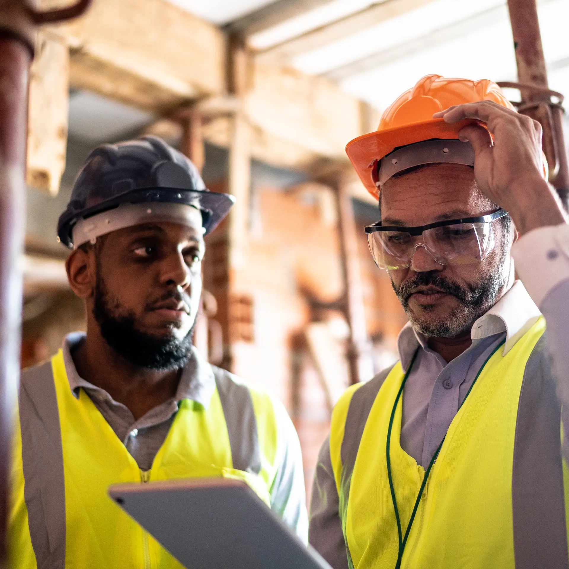 Two blue collar workers looking at a tablet.