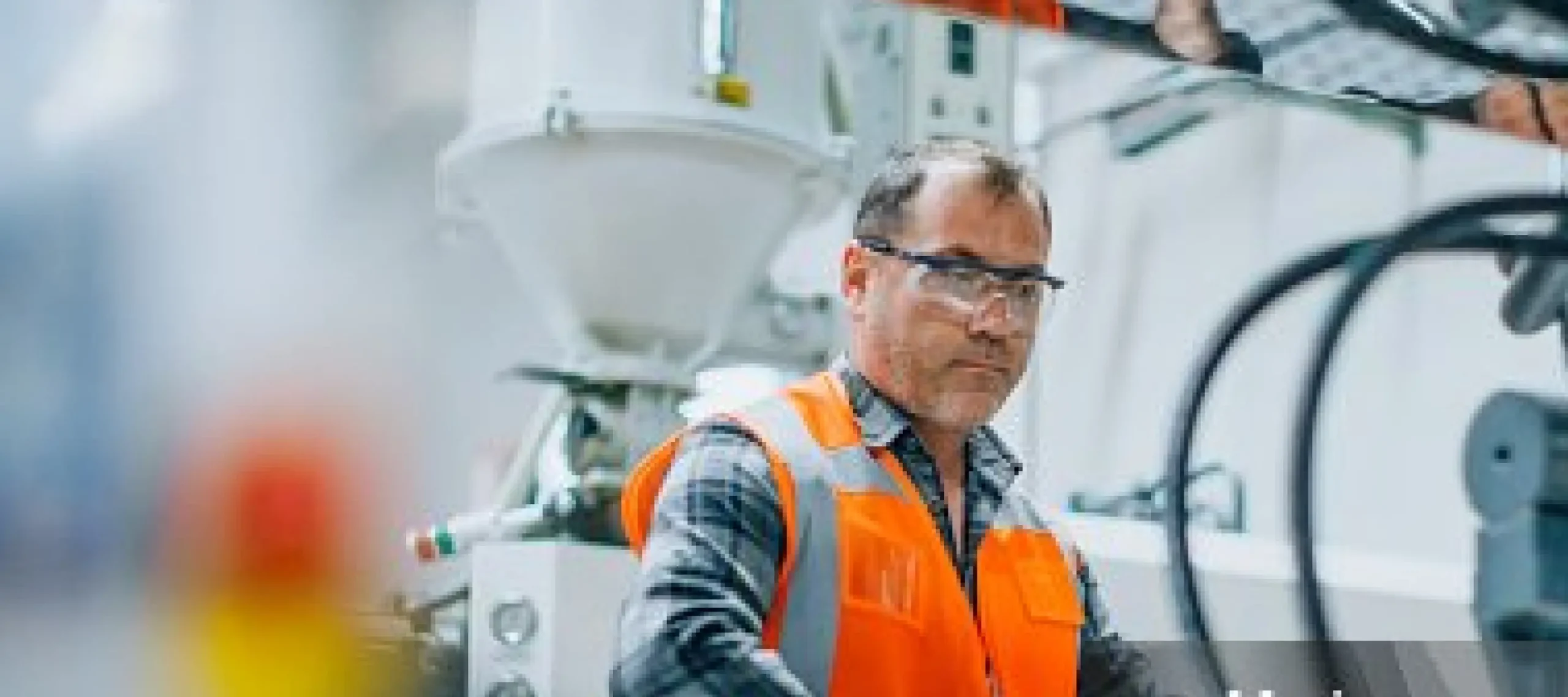 Worker wearing protective eyewear while working on a machine.