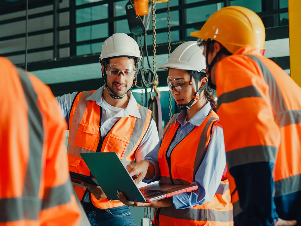 A group of blue collar workers looking at a computer.