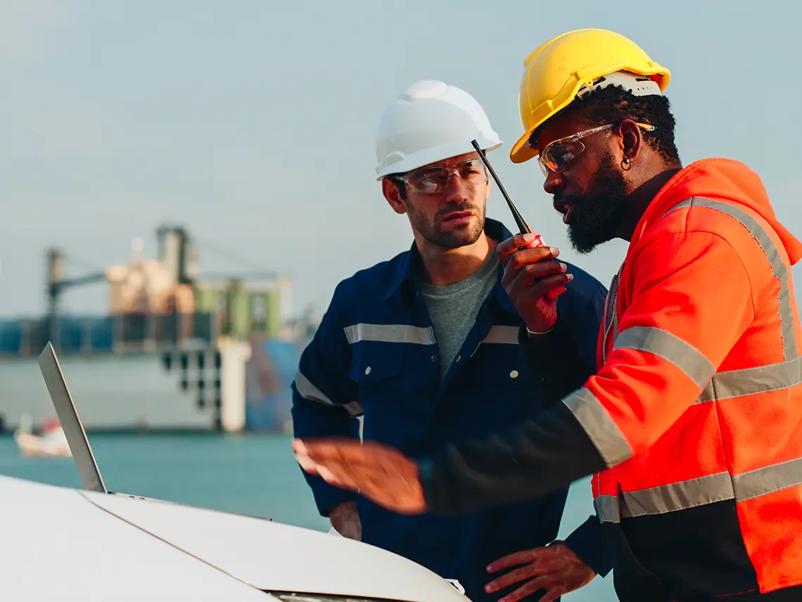 Two blue collar workers looking at a computer screen together.