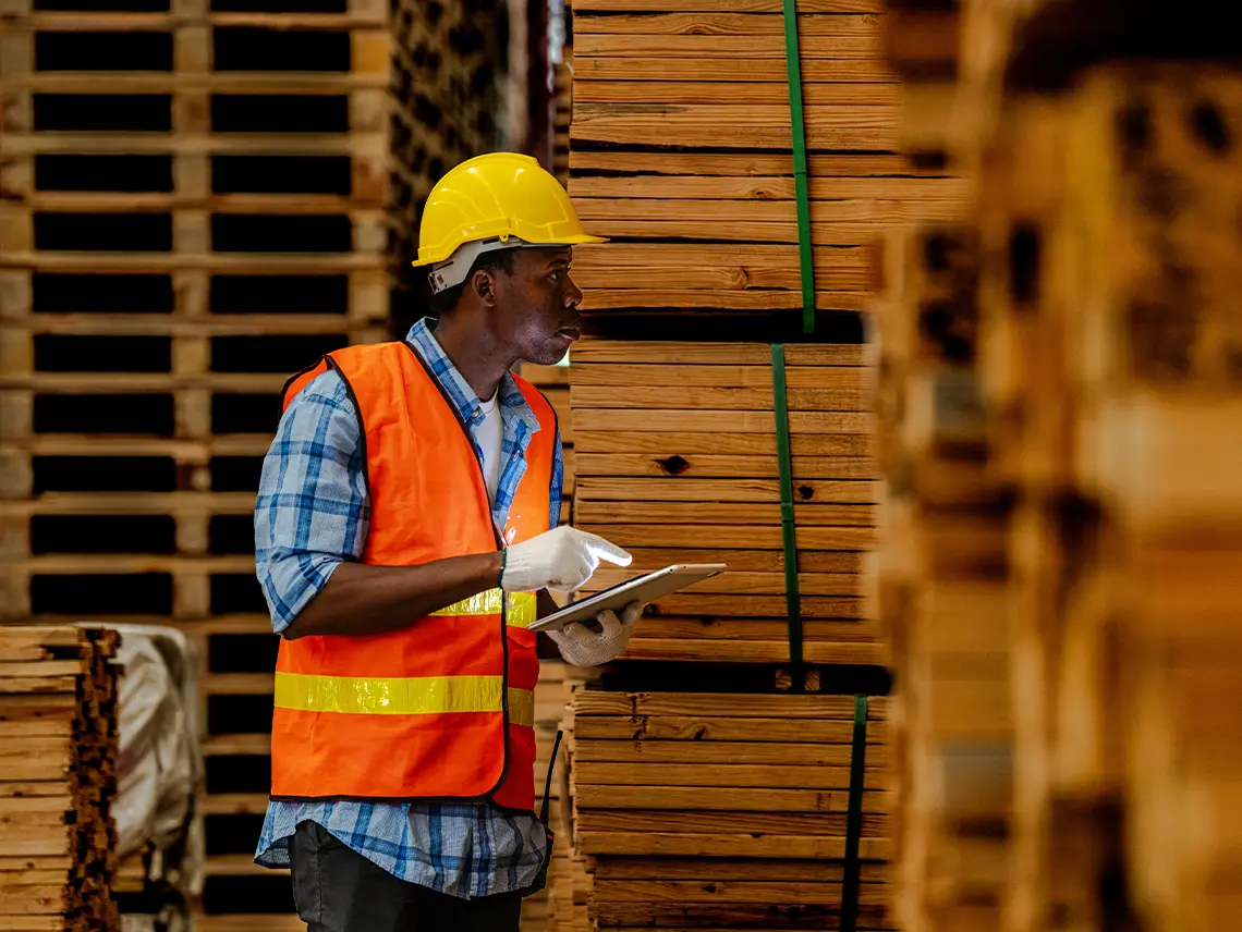 A construction worker standing next to a stack of pallets.