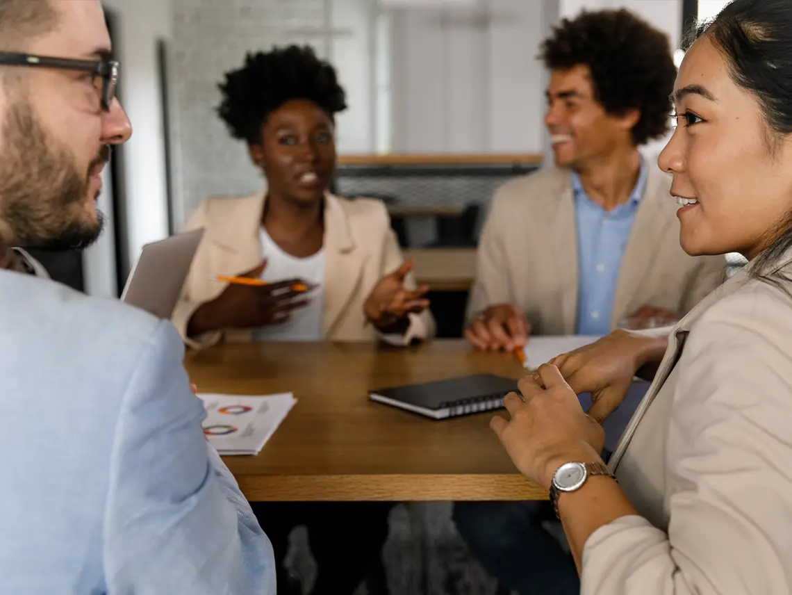 Four professionals talking in a meeting room.