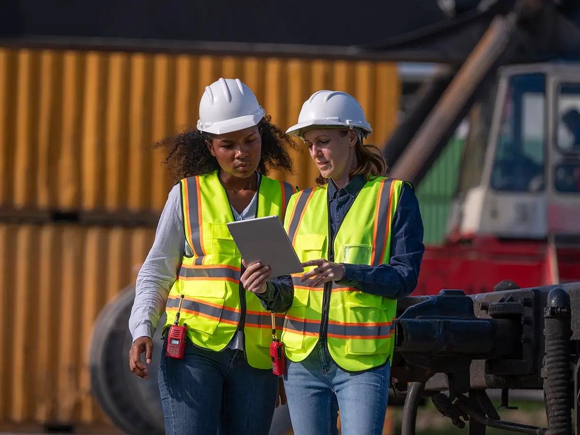 Two blue collar workers looking at a tablet together.