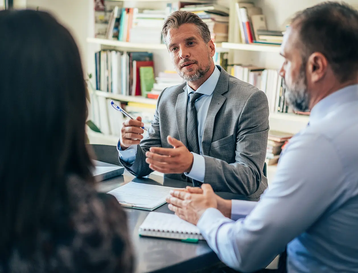 A man in a suit speaking with two clients.