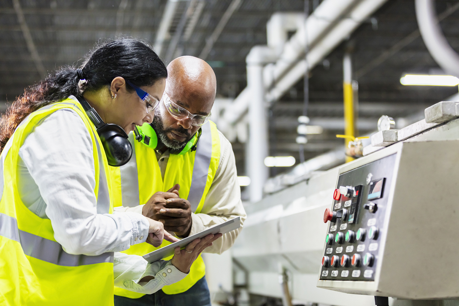 Multiracial workers in factory at machine control panel